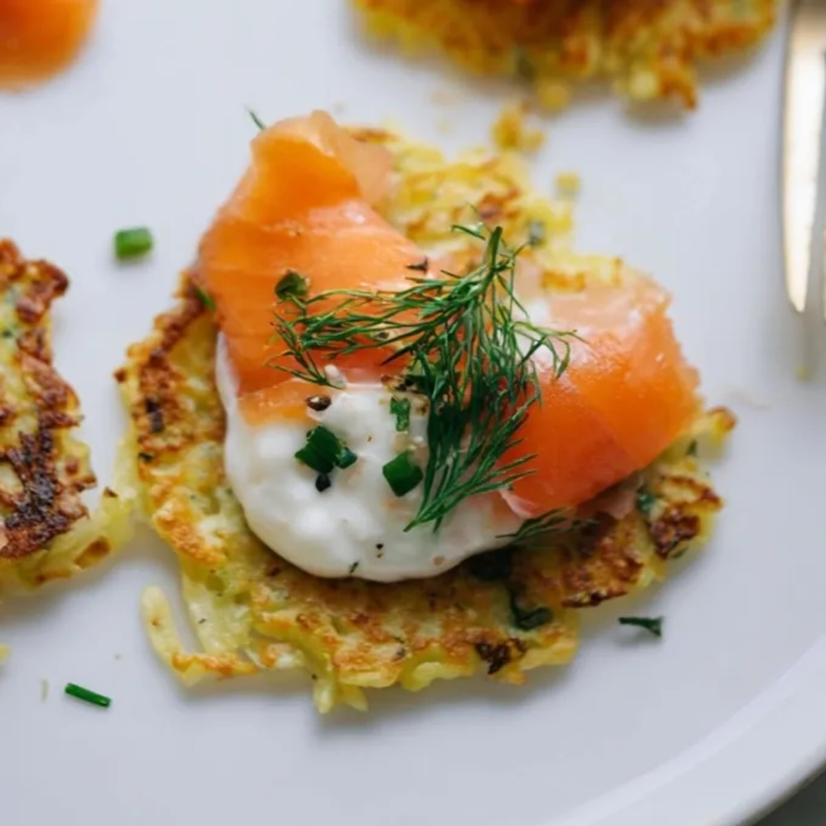 Knusprige Kartoffelpuffer mit Räucherlachs, garniert mit frischer Crème fraîche, ein köstlicher Genuss.