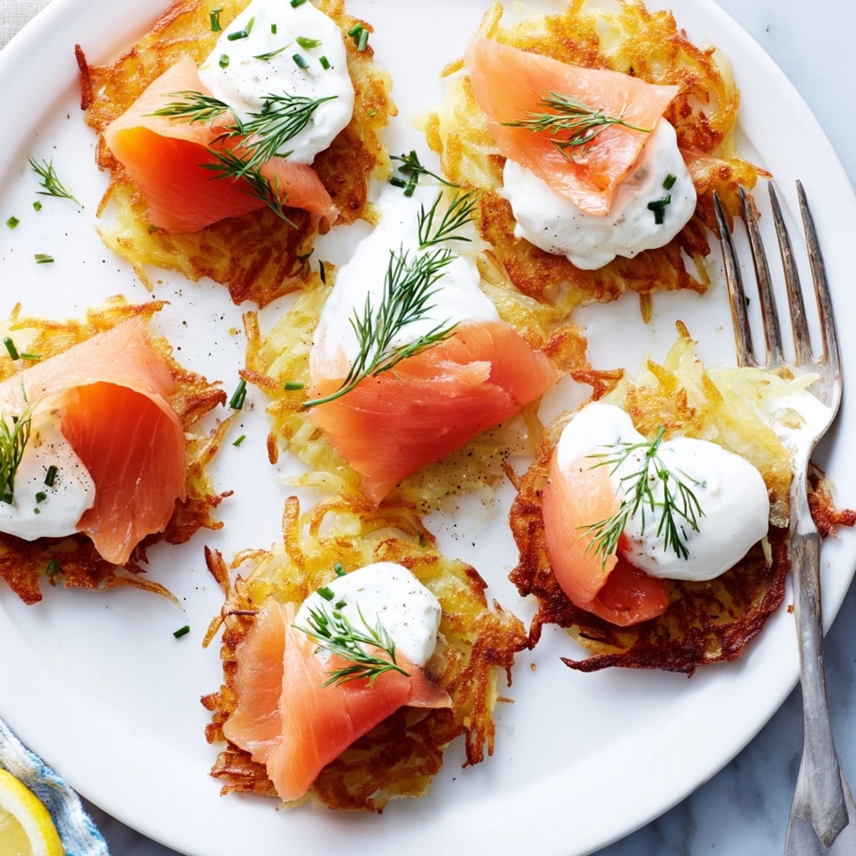 Ein Teller Kartoffelpuffer mit Räucherlachs, ein herzhaftes Gericht mit Zitronenzeste und frisch gehacktem Schnittlauch.