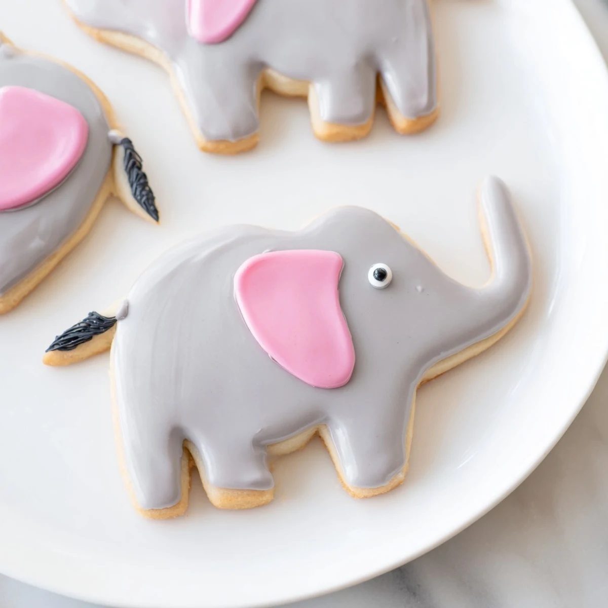 Giant elephant-shaped Biscuits Amical Éléphant Géant, frosted with gray and pink icing, look delightful.