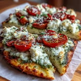 Gaumenfreude: Viral Cottage Cheese Flatbread mit leuchtendem Pesto, Tomatenstückchen und Kräutern.