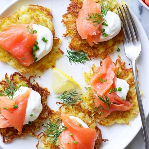 Goldbraune Kartoffelpuffer mit Räucherlachs und Dill, perfekt für einen Brunch oder als Vorspeise.