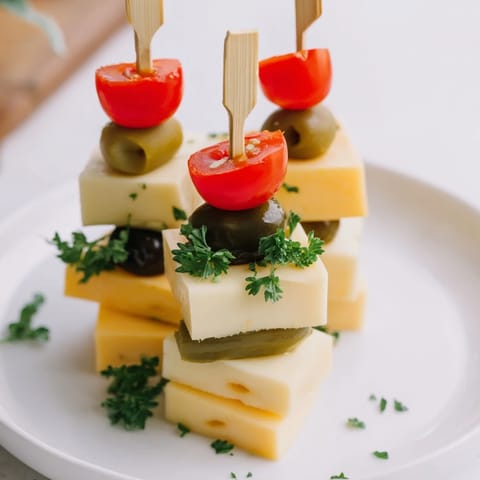 The Festive Cube Cheese Stack is a vibrant appetizer, featuring cheese and garnishes, ready to eat.
