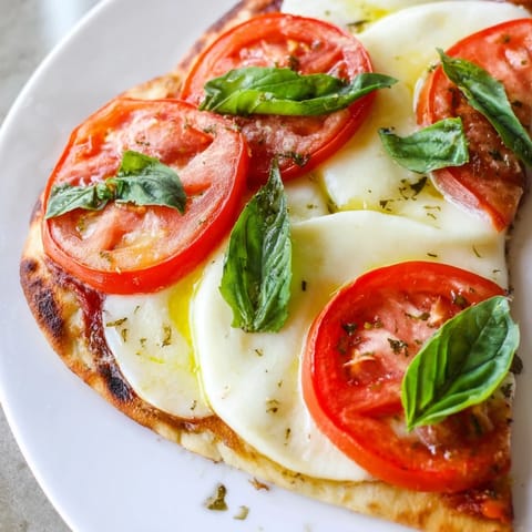 Enjoy a quick Margherita Naan Pizza with melted mozzarella over a crispy naan base, fresh from the oven.