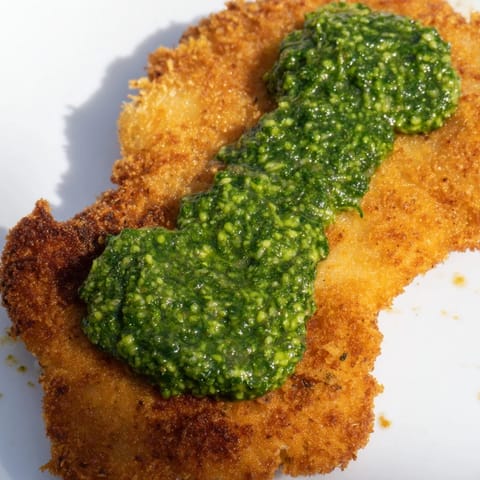 Kross gebackene Crispy Pesto Chicken Cutlets, üppig mit Parmesan-Panade umhüllt und mit frischen Basilikumblättern belegt für eine wochenendtaugliche Mahlzeit.