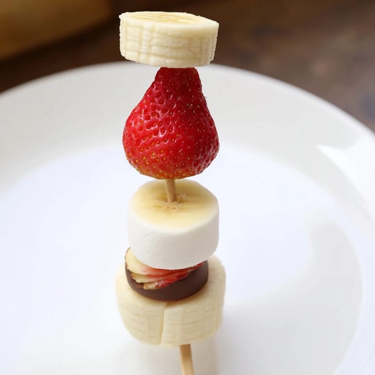 Köstliche Erdbeer-Bananen-Santa-Sticks, die aussehen wie kleine Weihnachtsmann-Hüte, perfekt für Kinder.