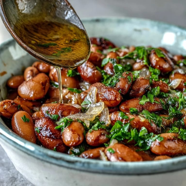 Gedünstete Pinto Bohnen mit Lorbeerblättern und Olivenöl, serviert warm mit frischen Kräutern im Schälchen.